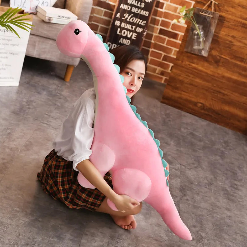 Child holding a large pink dinosaur plush toy in a room with a brick wall and wooden floor.