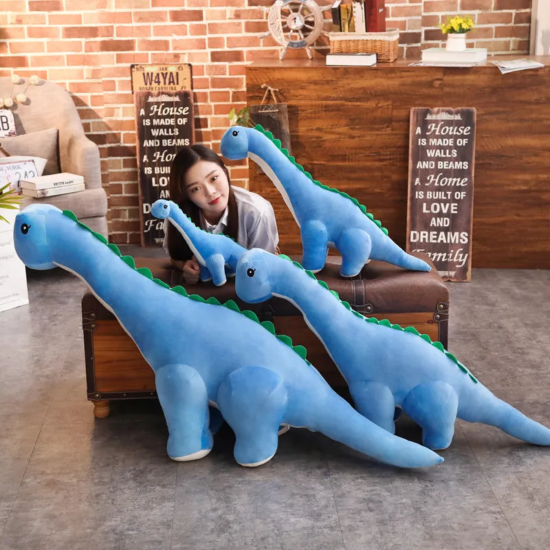 Blue dinosaur plushies in different sizes arranged on a wooden bench in a room with a brick wall and plants.